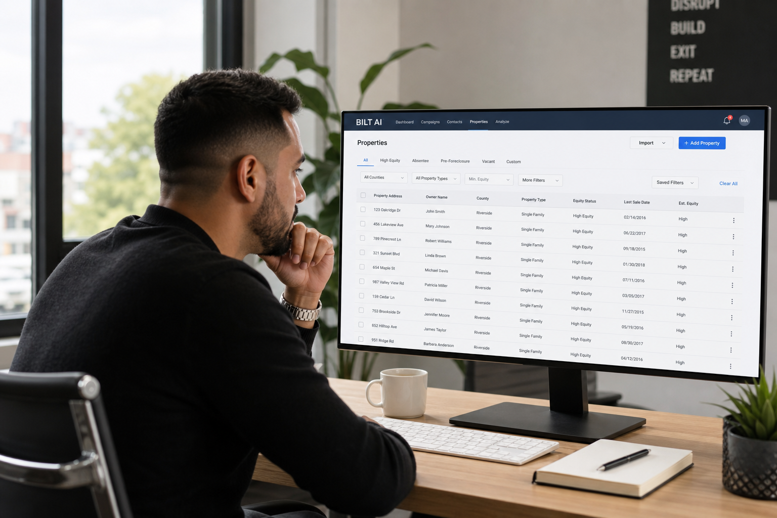 real estate investor reviewing a focused list of property records on a large monitor, spreadsheet filtered, minimal clean workspace, daylight office scene
