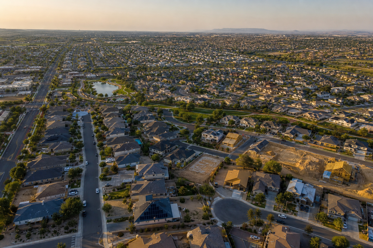 aerial view of a sprawling metro suburb with mixed new construction and older homes, late afternoon light, realistic urban sprawl